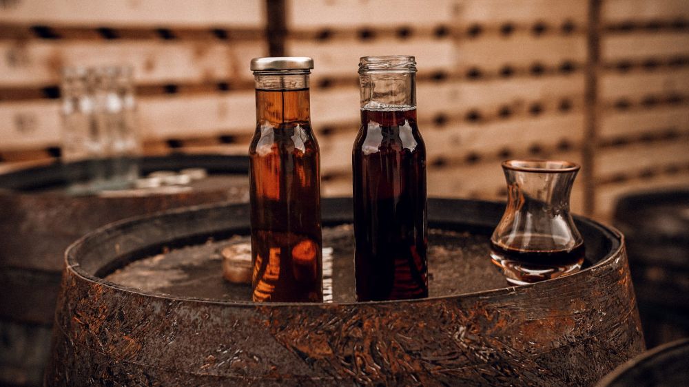 A whiskey glass and two bottles of Irish whiskey sitting on a whiskey investment cask